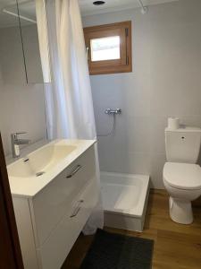 a white bathroom with a toilet and a sink at Cozy 2-Bedroom Bungalow in Interlaken