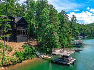 ein Haus auf einem Fluss mit Booten im Wasser in der Unterkunft Misty Trail Lakehouse - Lake Blue Ridge Luxury Home - Private Dock Firepit in Morganton