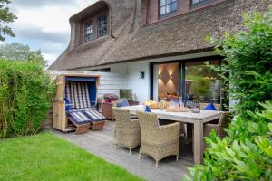 a patio with a table and chairs and a house at Reethüs Syltliebe in Morsum