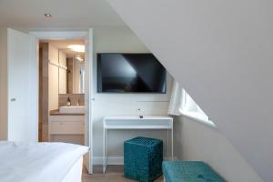 a bathroom with a sink and a tv on the wall at Reethüs Syltliebe in Morsum