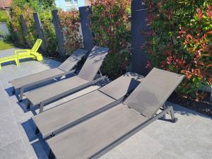 four lounge chairs are lined up on a patio at L'oasis de Dalhunden - Logement privé dans villa avec Piscine in Dalhunden