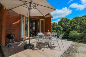 a patio with a table and chairs and an umbrella at Chalet Pondok Indah in Plouégat-Moysan
