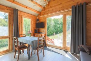 a dining room with a table and chairs and large windows at Chalet Pondok Indah in Plouégat-Moysan