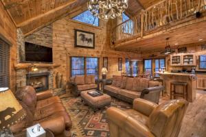 a living room with leather furniture in a log cabin at Sassafras Lodge - Cabin in North GA - Pet Friendly - Hot Tub, Fireplace, Mountain Views, Gas Griddle, Outdoor Fire Pit, Shuffleb in Mineral Bluff
