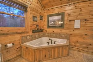 a bathroom with a tub in a wooden cabin at Sassafras Lodge - Cabin in North GA - Pet Friendly - Hot Tub, Fireplace, Mountain Views, Gas Griddle, Outdoor Fire Pit, Shuffleb in Mineral Bluff +46 photos