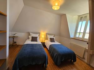 two beds in a small room with two windows at Villa Bajocasse, maison Bayeux Centre Historique - 4 chambres in Bayeux