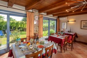 a dining room with tables and chairs and large windows at Cascina Giardini in Alba