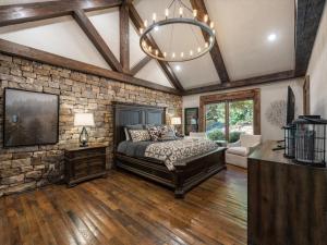 a bedroom with a stone wall and a bed and a chandelier at River Joy Lodge - Luxury Home on the Ellijay River in Cherry Log
