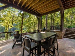 a wooden table and chairs on a patio with trees at River Joy Lodge - Luxury Home on the Ellijay River in Cherry Log