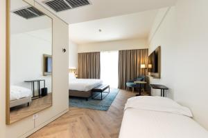 a hotel room with two beds and a mirror at Crowne Plaza - Caparica Lisbon in Costa da Caparica