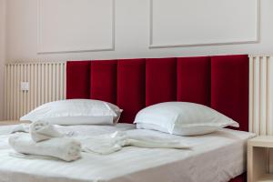 a bed with a red headboard and two white pillows at Sea View Apartments ELDO in Durrës