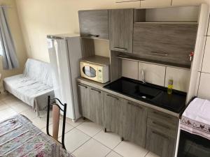 a small kitchen with a sink and a microwave at Geminado da mada casa 3 in Penha