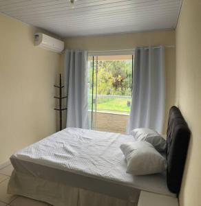 a bed in a room with a window at Geminado da mada casa 3 in Penha