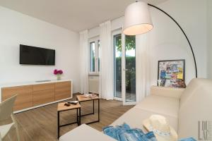een woonkamer met een witte bank en een tv bij Belle Maison - Du Lac Apartments in Sirmione