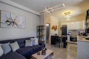 a living room with a blue couch and a kitchen at Envy Luxury Suite in Agia Pelagia
