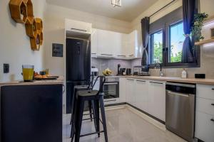 a kitchen with white cabinets and a black refrigerator at Envy Luxury Suite in Agia Pelagia +24 photos