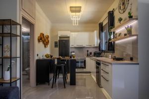 a kitchen with white cabinets and a black island at Envy Luxury Suite in Agia Pelagia