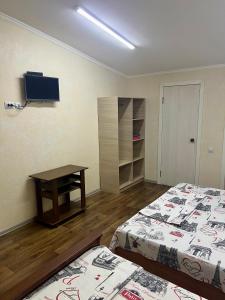 a room with two beds and a table and a tv at Гостевой дом Сафар in Kapchagay