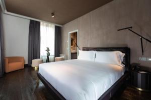 a bedroom with a large white bed and a chair at Palazzo Utini in Noceto