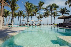 a swimming pool with palm trees and umbrellas at Arennas Mancora in Máncora