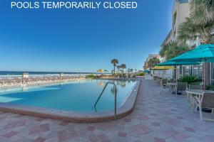 - une piscine avec des tables et des parasols à côté de la plage dans l'établissement Daytona Beach Resort 260, à Daytona Beach