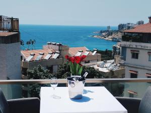 a table with a vase with red flowers on a balcony at Mateus Hotel in Jounieh