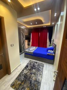 a bedroom with a blue bed and a red curtain at Villa in Stella Heights - North Coast in El Alamein