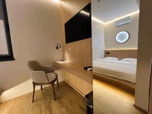 a room with a bed and a chair and a television at ALEM Hotel in Almaty