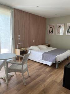 a bedroom with a bed and a table and chairs at Les Alcyons in Le Lavandou