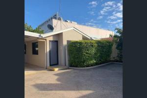 un edificio bianco con un cancello e una siepe di Fully Furnished Modern Unit in centre of city a Emerald