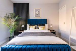 a bedroom with a large bed with a blue headboard at Glasswing Stays Margaret st, central Sheffield in Sheffield