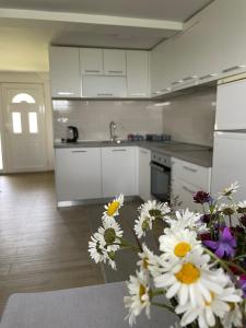 a kitchen with white cabinets and flowers in the foreground at Montenegro High Mountain Apartment in Žabljak
