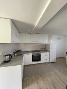 a kitchen with white cabinets and a sink at Montenegro High Mountain Apartment in Žabljak