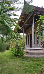 una pequeña casa con porche y algunas plantas en West Bali Menjangan Tour, en Pemuteran