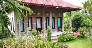 una pequeña casa con un jardín frente a ella en West Bali Menjangan Tour, en Pemuteran