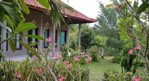 Una casa con flores rosas en el frente. en West Bali Menjangan Tour, en Pemuteran