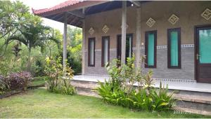 Un edificio con ventanas verdes y plantas en el frente. en West Bali Menjangan Tour, en Pemuteran