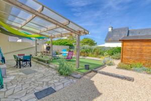 a patio with a wooden pergola and a table and chairs at Maison de vacances, 100m plage in Batz-sur-Mer