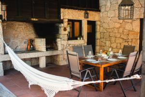 una mesa de madera con sillas y una hamaca en el patio en Casa da Terra - Gerês, en Gerês