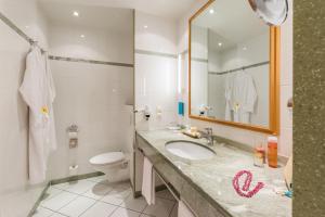 a bathroom with a sink and a toilet and a mirror at Strand-Hotel Hübner in Warnemünde