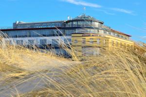 a building on top of a hill with tall grass at Strand-Hotel Hübner in Warnemünde