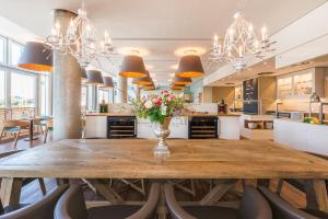 a large kitchen with a wooden table and chairs at Strand-Hotel Hübner in Warnemünde