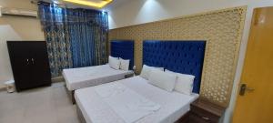 a bedroom with two beds and a blue headboard at AK Hotel Of Guest House in Lahore