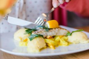 a person eating a plate of food with a fork and knife at Strand-Hotel Hübner in Warnemünde