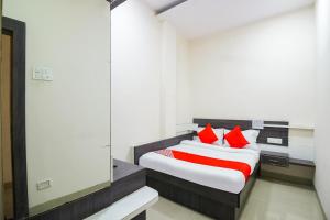 a bedroom with a bed with red pillows at Hotel O Unique Inn in Dhule