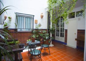 een patio met een tafel, stoelen en planten bij Pensión Santa María la Blanca in Sevilla