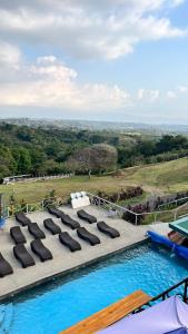 a pool with lounge chairs and a view of a field at Hotel Bar Restaurante IL Rifugio in Poás