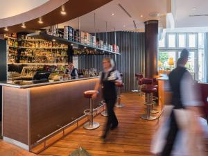 a woman walking past a bar in a restaurant at Strand-Hotel Hübner in Warnemünde