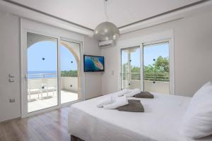 a white bedroom with a large bed and a balcony at Paradise Beach II in Kiotari +19 photos