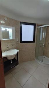 baño con lavabo, ducha y ventana en Amplia casa en La Falda, en La Falda 9 fotos más
